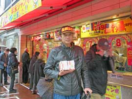 売場の前で今日買った東京2020ジャンボ宝くじを持って記念撮影